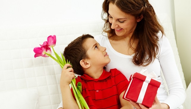 יום האם אמא מחזיקה קופסה מחבקת ילד מחזיק זר פרחים